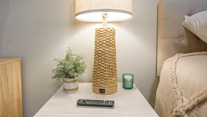 A bedside table with a lamp, a remote control, a small potted plant, and a candle. - Tallahassee Gem-Next to Doak and CollegeTown-Ideal for FSU weekend.3 minute walk (Tallahassee)