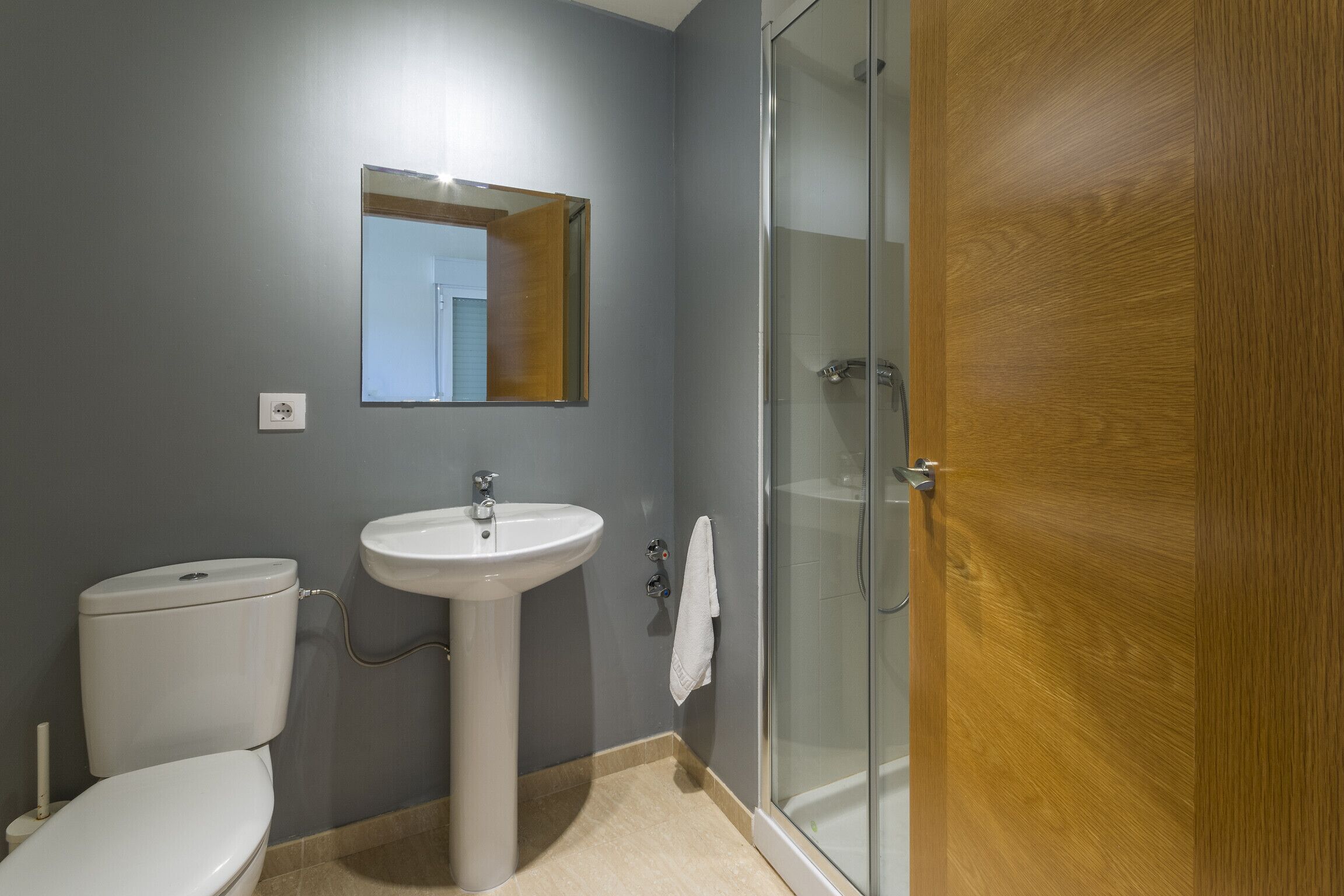 Un bagno con il water, lavabo, specchio e box doccia in vetro.