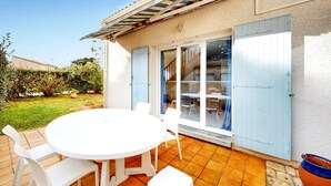 Une terrasse avec une table ronde et des chaises, une porte-fenêtre coulissante et un sol carrelé.