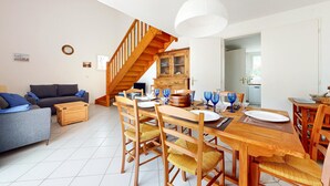Un vaste espace de vie agrémenté d’un escalier en bois, d’une table à manger mise en scène avec de la verrerie bleue et d’un canapé confortable.