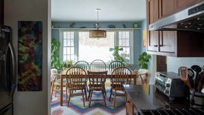 A kitchen with wooden cabinets, a dining table with chairs, a refrigerator, and a toaster.