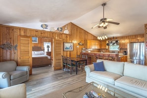 A cabin interior with a wooden interior, a dining area, a kitchen, and a living room with a sofa and chairs. - 🌴 Prime Summer Availability | Relax, Unplug & Enjoy the Coast (Alligator Point)