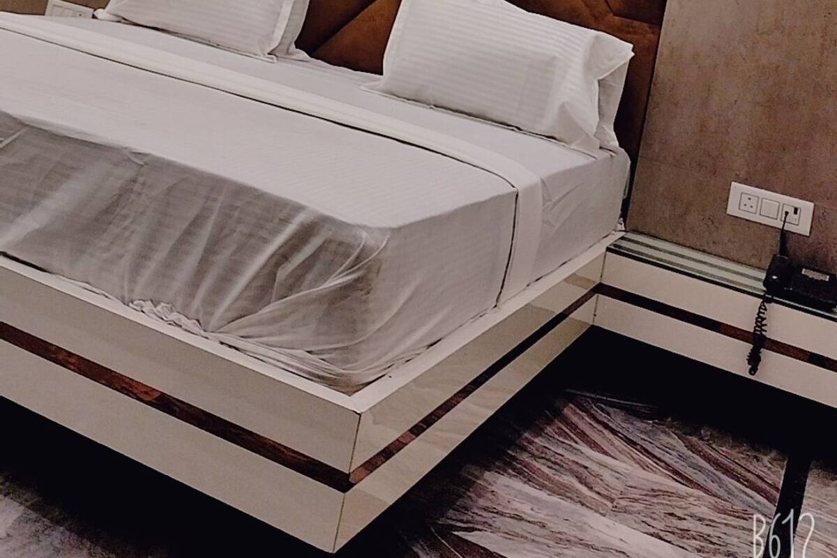 Um quarto moderno com uma cama grande, cabeceira com padrão geométrico e luminária embutida no teto.