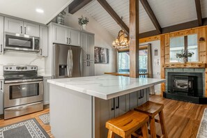 A modern kitchen with stainless steel appliances, a marble island, and a wooden bench. - Sunshine Village #108- 1 +Loft , Sleeps 6.  Steps from Free Town Shuttle ,Dog Friendly (Mammoth Lakes)