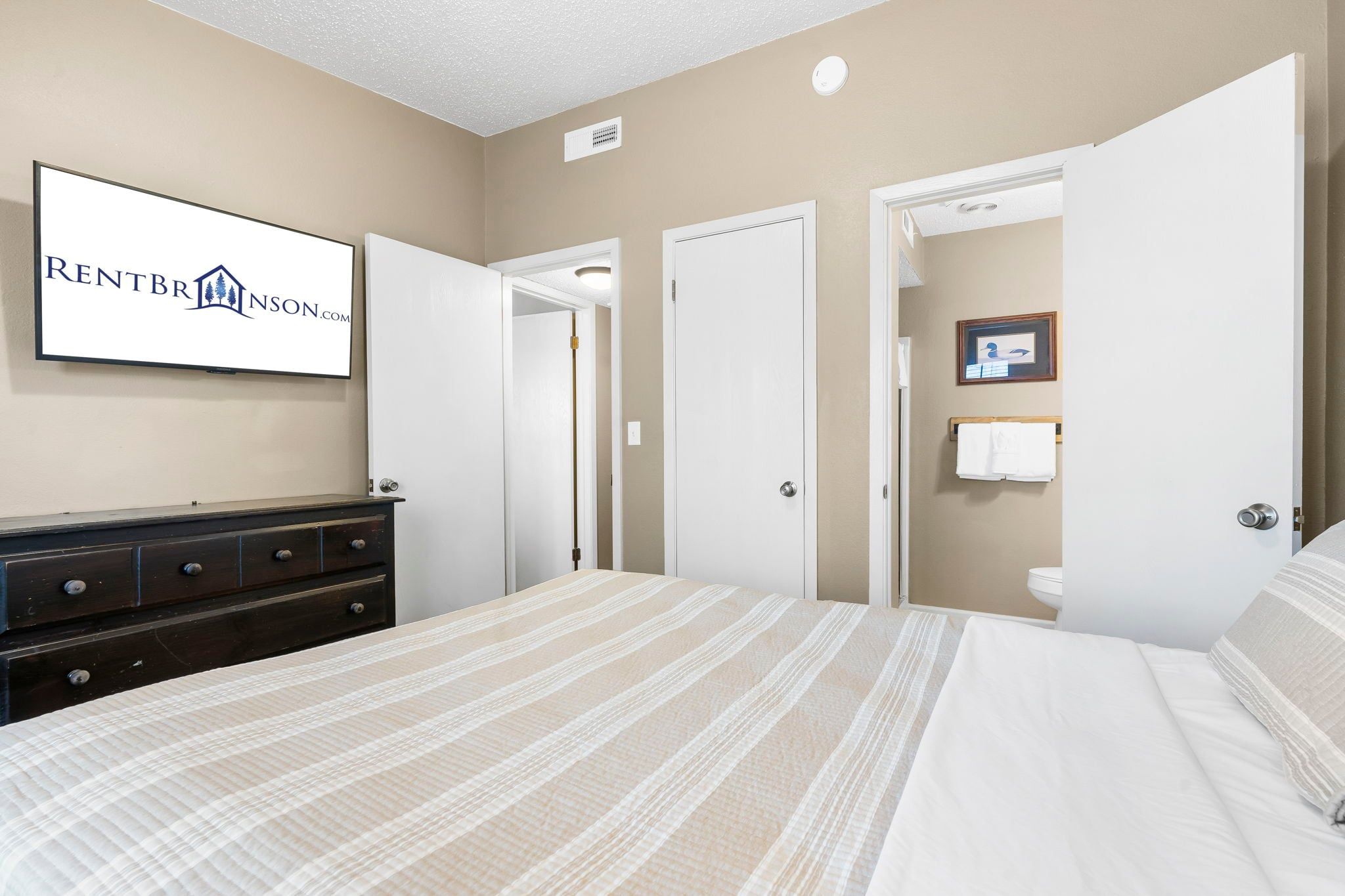 A bedroom with a bed, dresser, and a framed sign on the wall.
