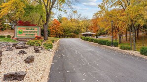 A sign for Ozark Mountain Resort with a paved road leading to a building.