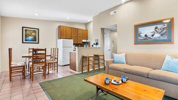 A compact living space with a kitchenette, a dining area, and a seating area with a sofa and coffee table.