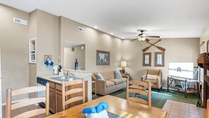 A compact living space with a kitchenette, a dining area, a sofa, and a television.