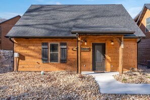 A wooden cabin with a sloped roof, a front door, and a small porch.