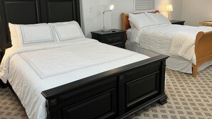 A hotel room with two beds, each with white bedding and wooden headboards. There are bedside tables with lamps and a wall-mounted light. The room has a patterned carpet and a window with blinds. - Home in Washington DC, 2 bedrooms, 4 beds, 2 baths,sleeping 5 & free parking. (Washington)