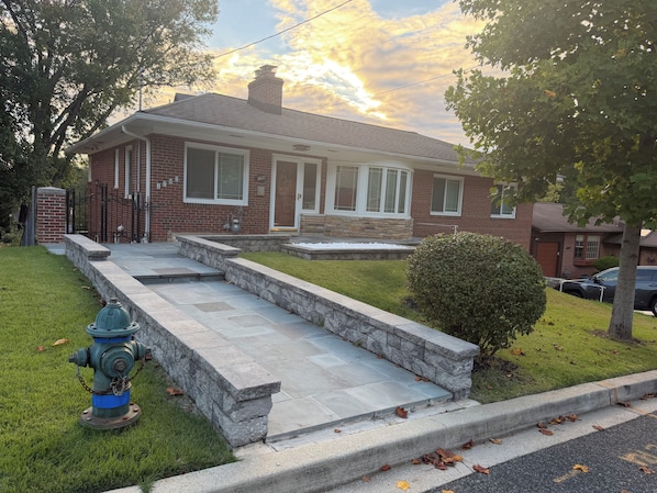 A residential house with a brick exterior, a front porch, and a fire hydrant on the lawn.