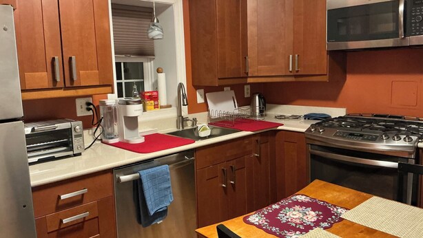 A compact kitchen with wooden cabinets, a built-in microwave, a gas stove, a toaster oven, and a coffee maker. - Home in Washington DC, 2 bedrooms, 4 beds, 2 baths,sleeping 5 & free parking. (Washington)