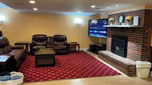 A living room with leather sofas, a coffee table, a red patterned rug, a fireplace, and a flat-screen TV mounted on the wall. - Home in Washington DC, 2 bedrooms, 4 beds, 2 baths,sleeping 5 & free parking. (Washington)