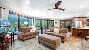 A spacious living room with a large window, a ceiling fan, and a kitchen area. - Charming Mountain Escape near Lake Cascade (Cascade)