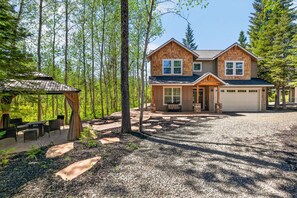 A two-story house with a covered patio, a garage, and a gravel driveway.
