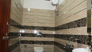 A bathroom with a toilet, sink, and marble walls. - Hotel Yubraj (Puri)