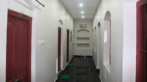 A narrow hallway with red doors, white walls, and a marble floor. - Hotel Yubraj (Puri)
