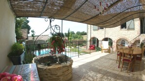 Un espace extérieur aménagé en terrasse, avec une table, des chaises, un barbecue et une piscine en arrière-plan.