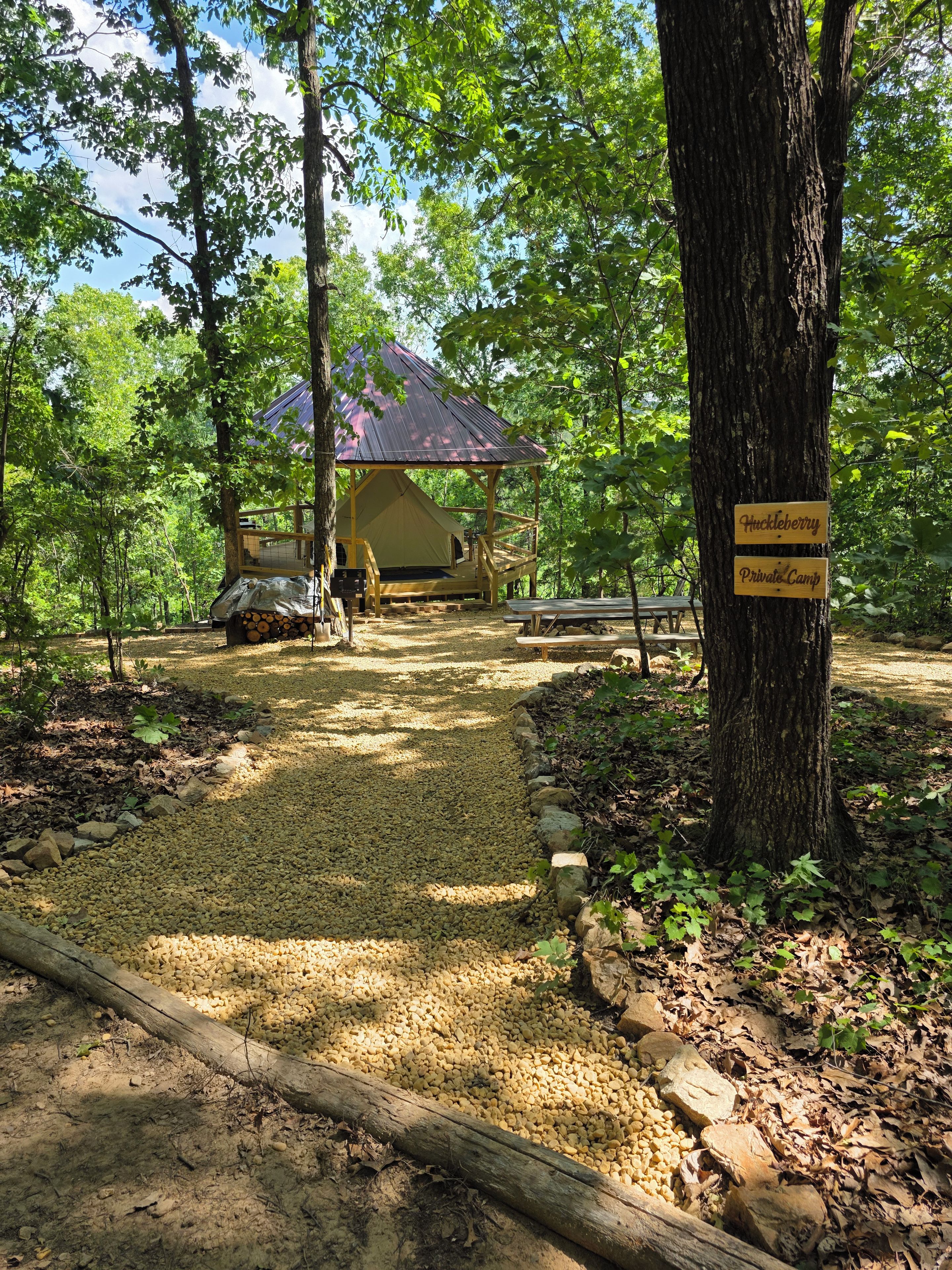 A campsite with a tent, picnic tables, and a sign indicating a private camp.