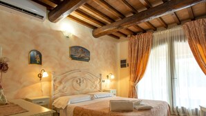 Habitación de hotel con cama, mesitas de noche, lámpara, un cuadro y una ventana con cortinas.