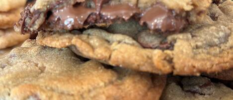 A stack of chocolate chip cookies with one broken in half, revealing a gooey chocolate center.