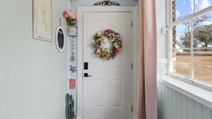 A white door with a floral wreath, a 'Hello Gorgeous' sign, and a 'Home' sign above it. -  Luxury Country Stay - Indoor heated pool, Spa, Art Studio, Breakfast, Hot Tub (Chipley)