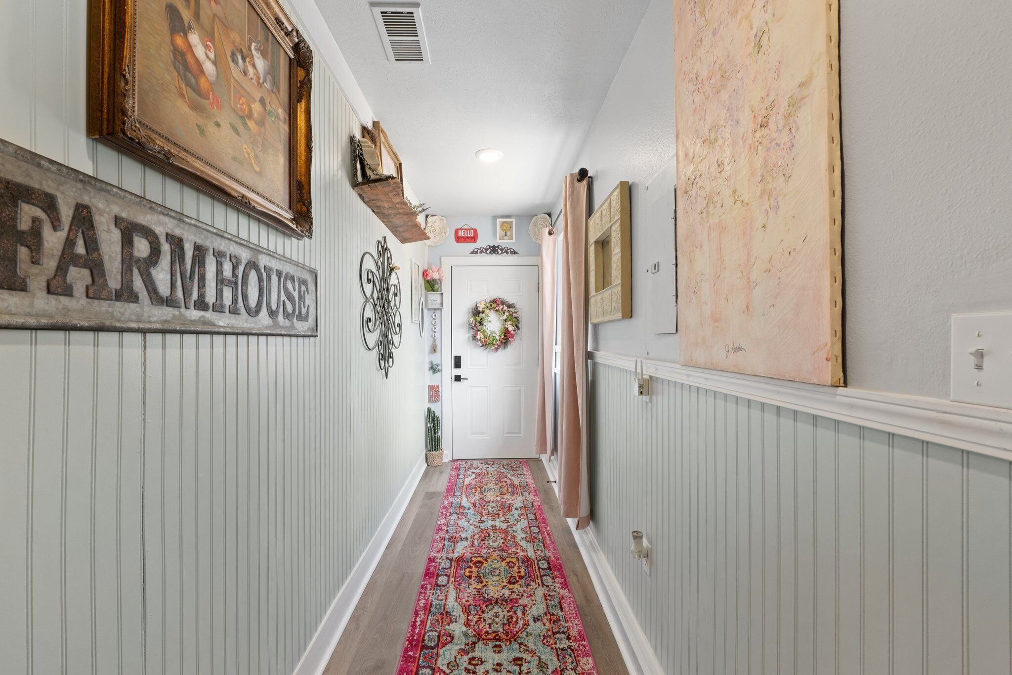 Un couloir orné d’une enseigne évoquant une ferme, d’une guirlande décorative et d’un tapis à motifs.