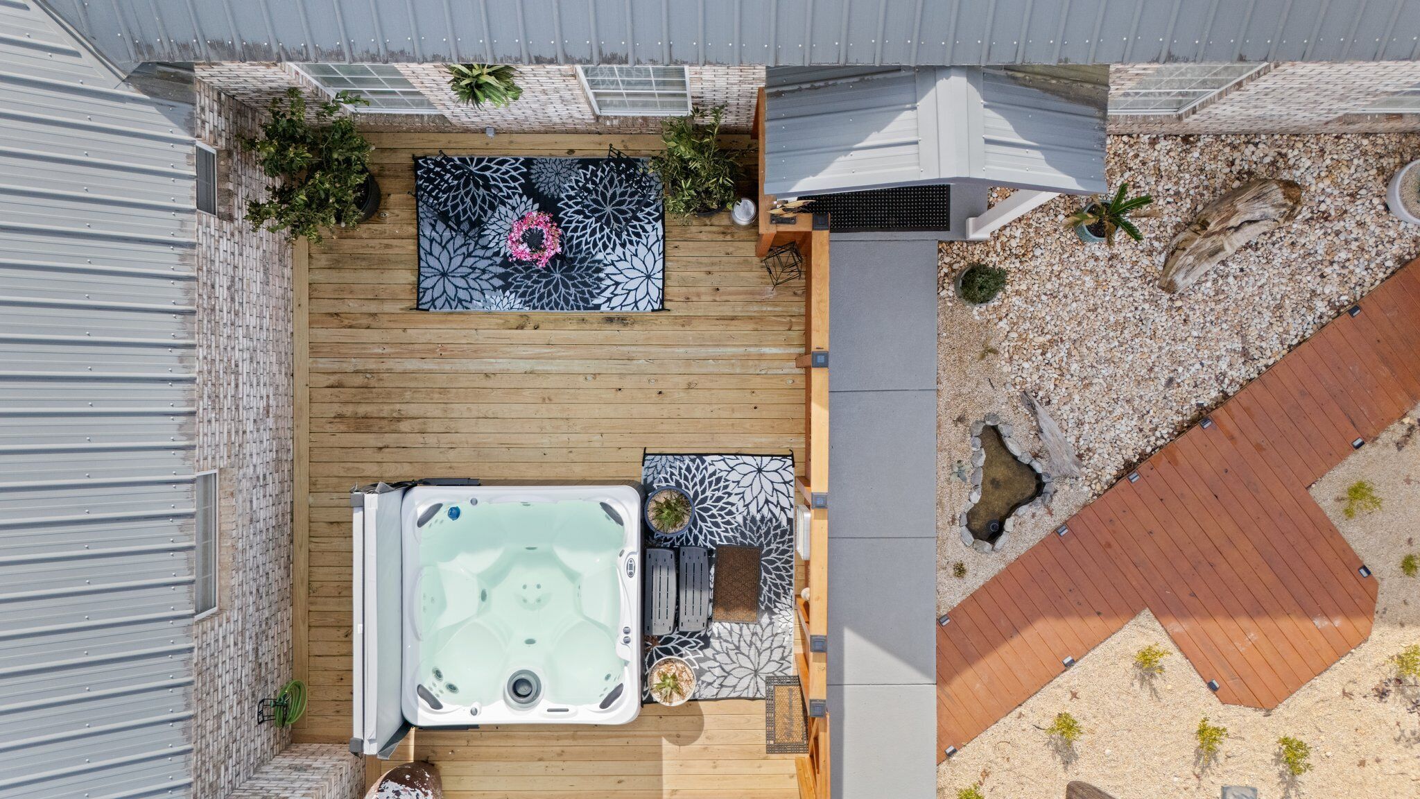 A rooftop patio with a hot tub, seating area, and potted plants.