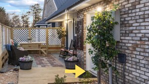 A wooden deck leading to a brick house with a white lattice fence, outdoor seating, and potted plants. -  Luxury Country Stay - Indoor heated pool, Spa, Art Studio, Breakfast, Hot Tub (Chipley)