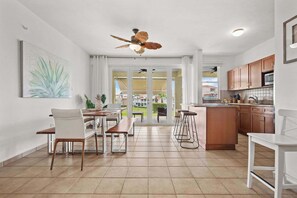 A modern kitchen with a central island, white cabinetry, and a dining area with a bench and chairs. - Lakeside Escape | Stylish Unit with BBQ and Pool (Humacao)