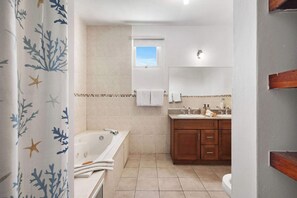 A bathroom with a bathtub, a window, and a sink with a mirror above it. - Lakeside Escape | Stylish Unit with BBQ and Pool (Humacao)