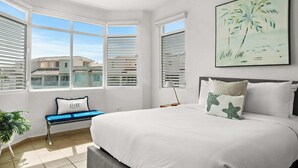 A bedroom with a large bed, a bench, and a window with blinds. - Lakeside Escape | Stylish Unit with BBQ and Pool (Humacao)