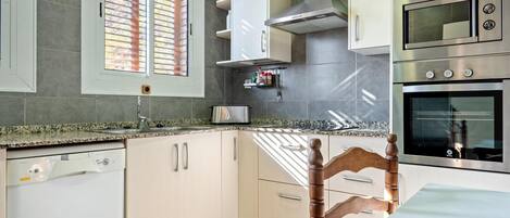 A modern kitchen with a dishwasher, double sink, and stainless steel appliances including a microwave and oven.
