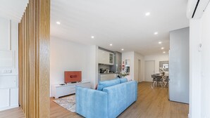 A modern living room with a blue sofa, a flat-screen TV, and a wooden partition.