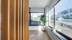A modern interior with a wooden panel wall, a large window with a view of a cityscape, and a potted plant.