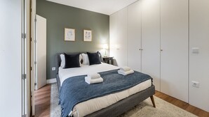 A bedroom with a bed, bedside tables, a wardrobe, and two framed pictures on the wall. - GuestReady - Restful haven in Porto (Porto)
