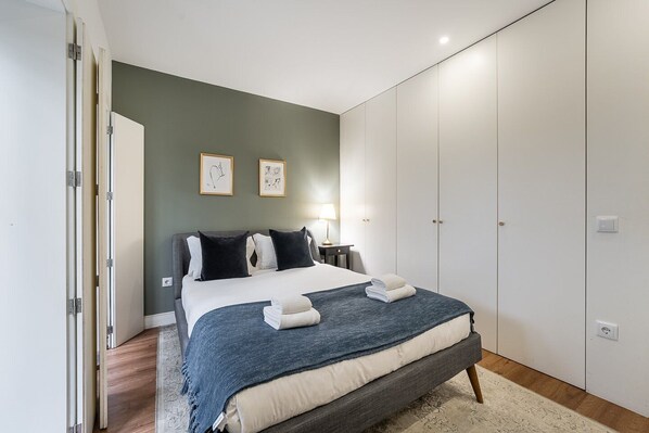 A bedroom with a bed, bedside tables, a wardrobe, and two framed pictures on the wall.