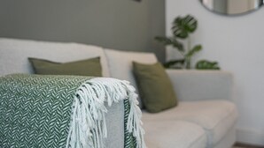 A living room with a white sofa, a green throw blanket, and a green pillow. - GuestReady - Restful haven in Porto (Porto)