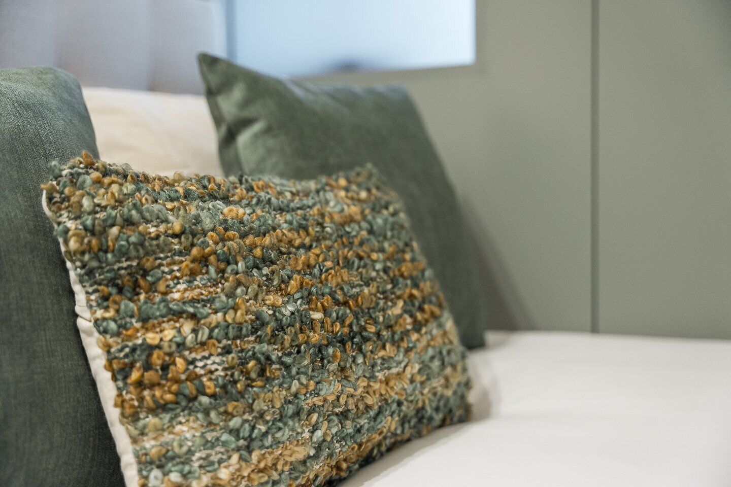Una cama con un cojín de textura y un cojín liso.