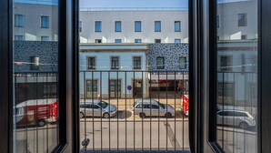 Vista a través de una ventana mostrando una calle con coches aparcados y edificios.
