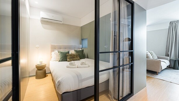 Un dormitorio moderno con cama, mesita de noche y sofá.
