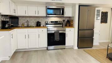 Une cuisine moderne avec des armoires blanches, des appareils en acier inoxydable et un plan de travail en bois.