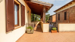 Un espacio al aire libre cubierto con una pérgola de madera, un edificio de ladrillo y suelo de baldosas.