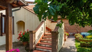 Una escalera conduce a un edificio de ladrillo con un jardín y macetas con plantas y flores.
