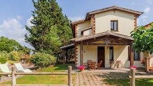 A two-story house with a covered patio, a wooden fence, and outdoor seating. - Apartment 'Amelia' with Shared Pool, Wi-Fi and Air Conditioning (Grosseto)