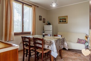 A dining area with a table, chairs, a refrigerator, and a sofa. - Apartment 'Amelia' with Shared Pool, Wi-Fi and Air Conditioning (Grosseto)