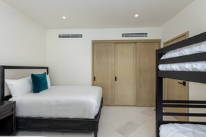 Quarto de hotel com uma cama de solteiro, mesa de cabeceira, guarda-roupa e cama beliche.