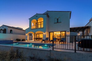 A two-story building with a swimming pool, outdoor seating, and a pergola.