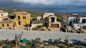 A residential area with houses featuring Mediterranean architecture, a paved driveway, and a view of the landscape.