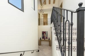 A staircase with black railings and patterned tiles, leading to a second floor.